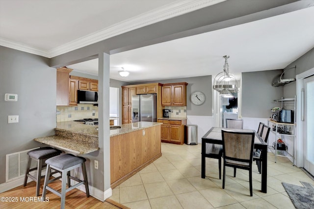 8 Shadow Ridge Ct, Howell, NJ 07731 - kitchen featuring stainless steel refrigerator with ice dispenser, brown cabinets, light stone counters, a peninsula, and a breakfast bar