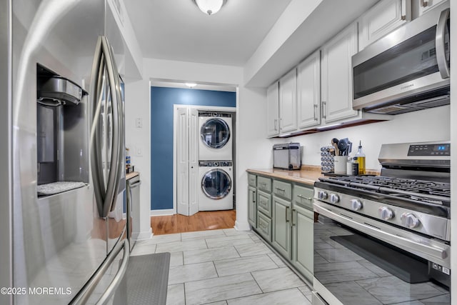 193 Sierra Ct, Woodbridge, NJ 07095 - kitchen featuring stainless steel appliances, estacked washer and dryer, white cabinetry, light countertops, and light marble finish flooring