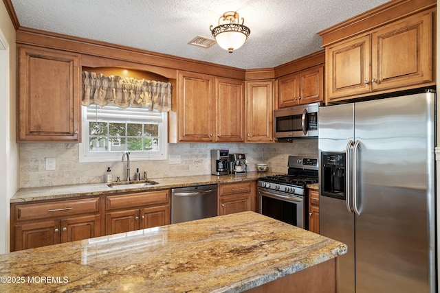54 Storm Jib Ct, Bayville, NJ 08721 - kitchen featuring appliances with stainless steel finishes, brown cabinetry, a textured ceiling, tasteful backsplash, and light stone countertops