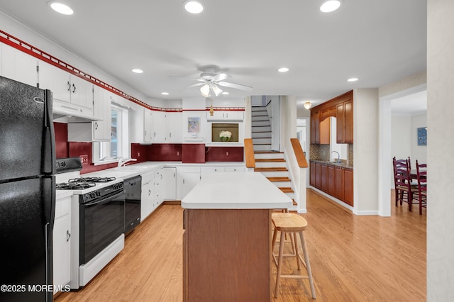 340 Main Ave, Bay Head, NJ 08742 - kitchen with black appliances, under cabinet range hood, a center island, a ceiling fan, and light wood-style floors
