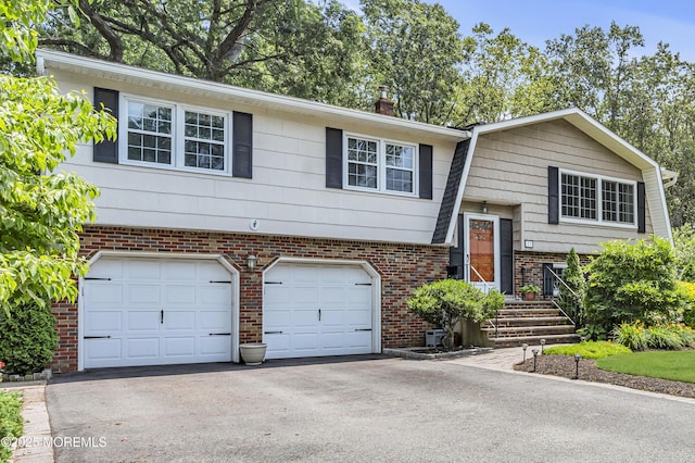 27 Greenhill Dr, Brick, NJ 08724 - raised ranch featuring a garage, driveway, brick siding, and a chimney