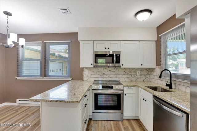 9 Deerfield Dr Unit D, Whiting, NJ 08759 - kitchen with appliances with stainless steel finishes, baseboard heating, a peninsula, decorative backsplash, and light wood finished floors
