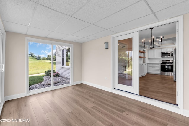 377 Old Nassau Rd Unit 377B, Monroe, NJ 08831 - empty room featuring a drop ceiling, light wood finished floors, a chandelier, and healthy amount of natural light