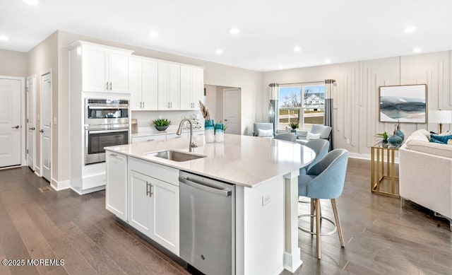 2705 Journey Ave, Marlboro, NJ 07746 - kitchen featuring appliances with stainless steel finishes, open floor plan, dark wood finished floors, a kitchen island with sink, and light countertops