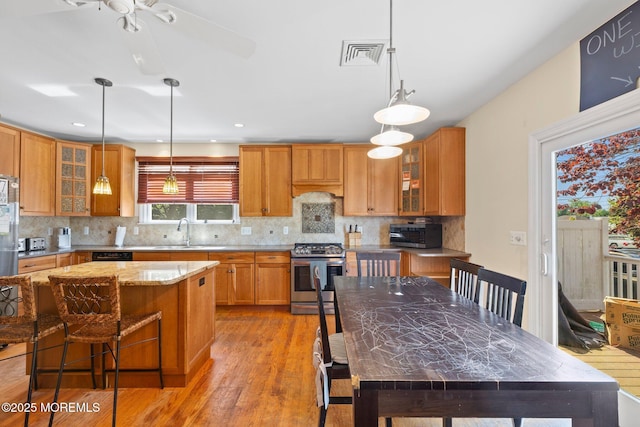 217 Alpern Ave, Elberon, NJ 07740 - kitchen featuring stainless steel appliances, light wood-type flooring, decorative backsplash, and brown cabinets