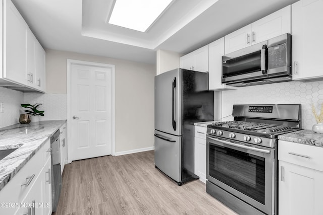 982 Thornbury Ln Unit B, Manchester, NJ 08759 - kitchen featuring appliances with stainless steel finishes, backsplash, white cabinetry, light wood-style floors, and light stone counters
