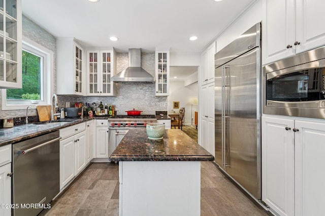11 Delwood Rd, Chester Twp, NJ 07930 - kitchen with wall chimney exhaust hood, built in appliances, a kitchen island, decorative backsplash, and dark stone counters