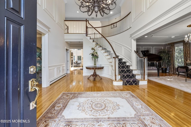 320 Sinclair Ct, Morganville, NJ 07751 - entrance foyer featuring a chandelier, stairs, wood finished floors, a baseboard heating unit, and a decorative wall