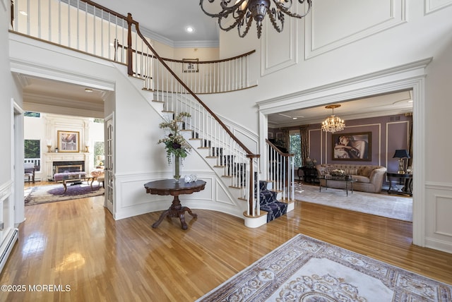 320 Sinclair Ct, Morganville, NJ 07751 - foyer featuring a decorative wall, stairway, wood finished floors, a chandelier, and a glass covered fireplace