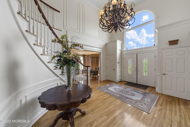 320 Sinclair Ct, Morganville, NJ 07751 - entrance foyer featuring a towering ceiling, stairs, a chandelier, wood finished floors, and a decorative wall