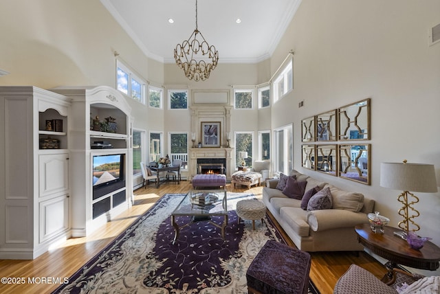 320 Sinclair Ct, Morganville, NJ 07751 - living room featuring a warm lit fireplace, light wood-style floors, a chandelier, a high ceiling, and ornamental molding