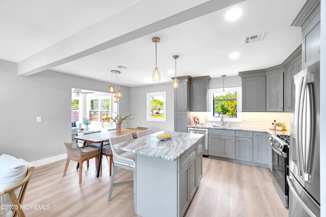 134 Northumberland Dr, Toms River, NJ 08757 - kitchen with gray cabinets, appliances with stainless steel finishes, light stone counters, backsplash, and a breakfast bar area