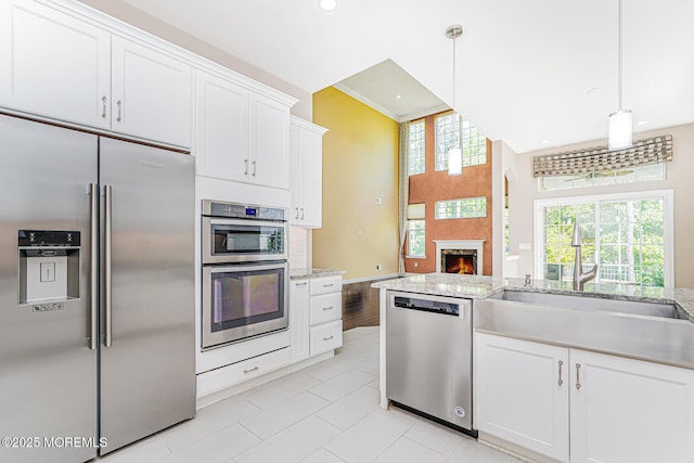 161 Arborridge Dr, Forked River, NJ 08731 - kitchen featuring appliances with stainless steel finishes, white cabinetry, light stone countertops, a warm lit fireplace, and recessed lighting