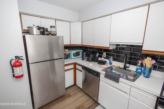 364 Westwood Ave Unit 46, Long Branch, NJ 07740 - kitchen with appliances with stainless steel finishes, light countertops, white cabinetry, decorative backsplash, and light wood-style flooring