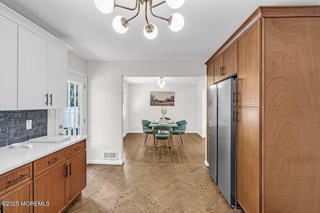 1528 Stuyvesant Ave, Ewing, NJ 08618 - kitchen featuring freestanding refrigerator, a chandelier, tasteful backsplash, and brown cabinetry