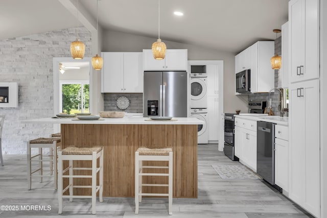 3 Casey Ct, Barnegat, NJ 08005 - kitchen with stacked washer / dryer, appliances with stainless steel finishes, vaulted ceiling, decorative backsplash, and a breakfast bar