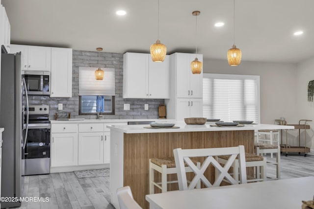 3 Casey Ct, Barnegat, NJ 08005 - kitchen featuring appliances with stainless steel finishes, backsplash, light wood-style floors, light countertops, and a breakfast bar