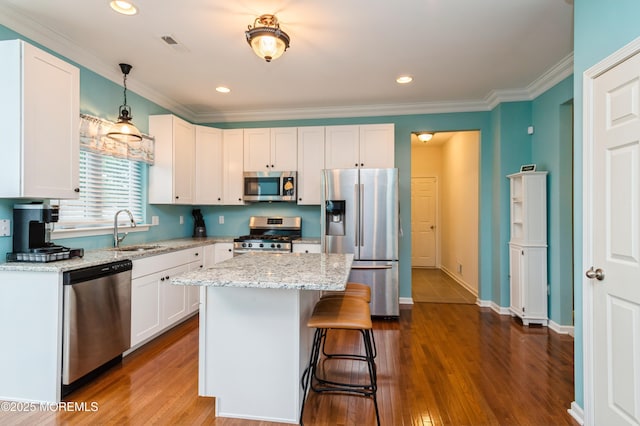 96 Bridle Path, Bayville, NJ 08721 - kitchen with stainless steel appliances, white cabinetry, ornamental molding, light stone counters, and a kitchen bar