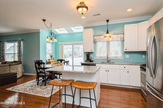 96 Bridle Path, Bayville, NJ 08721 - kitchen with appliances with stainless steel finishes, a breakfast bar area, a skylight, white cabinetry, and a chandelier