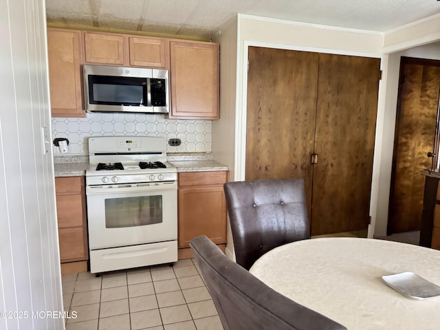 1408 Anvil Way, Toms River, NJ 08755 - kitchen with stainless steel microwave, white gas range oven, light countertops, light tile patterned floors, and decorative backsplash