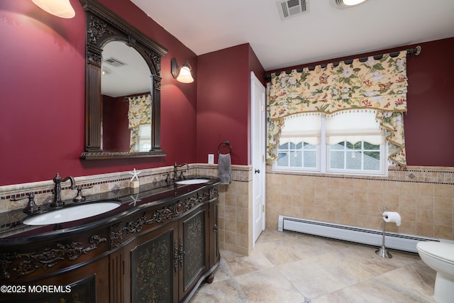 41 Cedar St, Keyport, NJ 07735 - bathroom with tile walls, a baseboard radiator, double vanity, wainscoting, and tile patterned floors