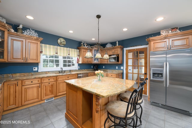 41 Cedar St, Keyport, NJ 07735 - kitchen with appliances with stainless steel finishes, a kitchen island, light stone countertops, a breakfast bar, and light tile patterned floors