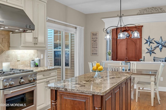 45 Erin Dr, Jackson, NJ 08527 - kitchen with under cabinet range hood, stainless steel stove, light stone counters, and backsplash