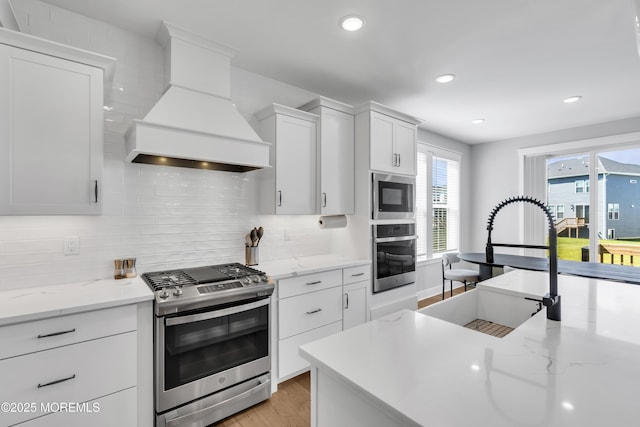 3 Devon Dr, Howell, NJ 07731 - kitchen featuring appliances with stainless steel finishes, custom range hood, light wood-style floors, decorative backsplash, and white cabinets