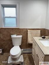 33 Tennent Ave, Englishtown, NJ 07726 - bathroom featuring baseboard heating, vanity, a wainscoted wall, and tile walls