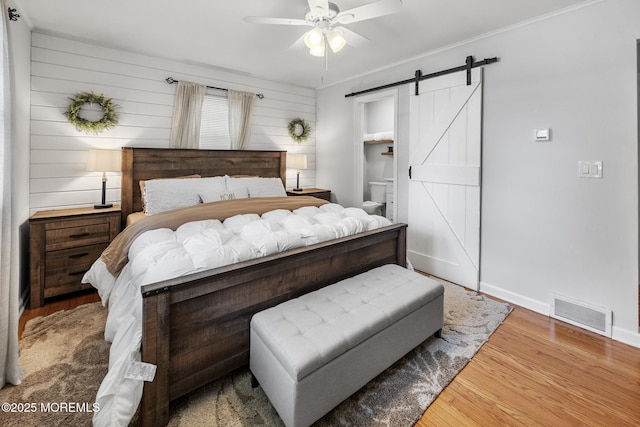 2120 Frances Dr, Point Pleasant, NJ 08742 - bedroom featuring a barn door, wood finished floors, ceiling fan, and wood walls