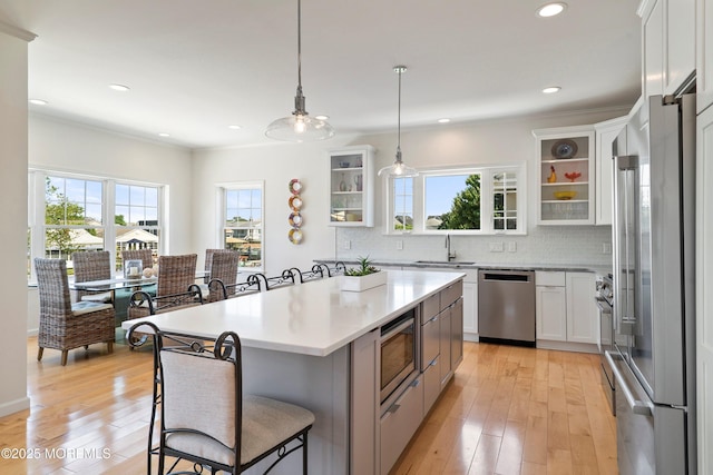 1735 Certainty Dr, Point Pleasant, NJ 08742 - kitchen with stainless steel appliances, a breakfast bar area, light wood finished floors, light countertops, and decorative backsplash