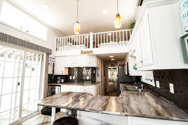 37 15th Ave, Seaside Park, NJ 08752 - kitchen with a towering ceiling, a peninsula, tasteful backsplash, white cabinets, and decorative light fixtures