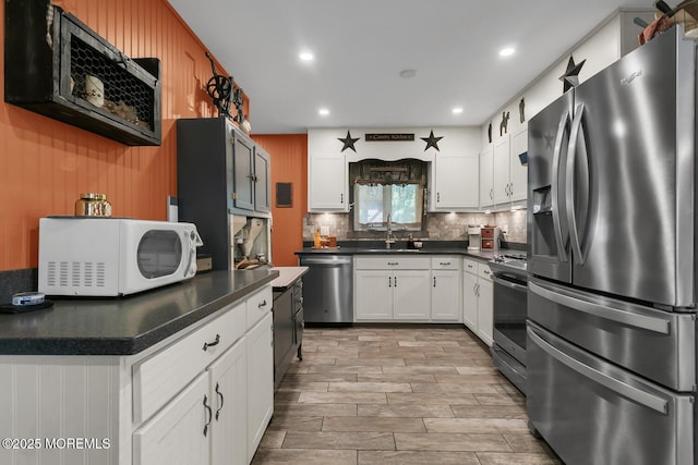 216 Main St, Port Monmouth, NJ 07758 - kitchen featuring appliances with stainless steel finishes, tasteful backsplash, dark countertops, white cabinets, and recessed lighting