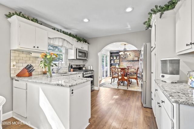 91 Newbury Rd, Howell, NJ 07731 - kitchen with stainless steel appliances, a chandelier, white cabinetry, arched walkways, and recessed lighting