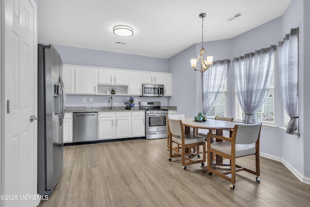 10 Ignatius Dr, Manchester, NJ 08759 - kitchen featuring appliances with stainless steel finishes, a chandelier, open shelves, white cabinets, and light wood finished floors