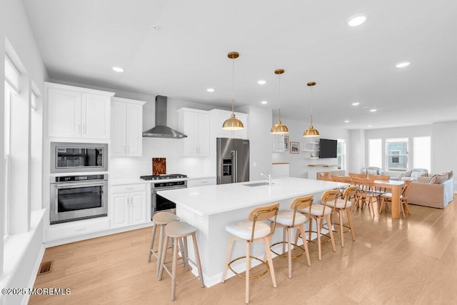 25 Signal Ave, Oceanport, NJ 07757 - kitchen with appliances with stainless steel finishes, wall chimney range hood, light wood-style flooring, a breakfast bar area, and recessed lighting