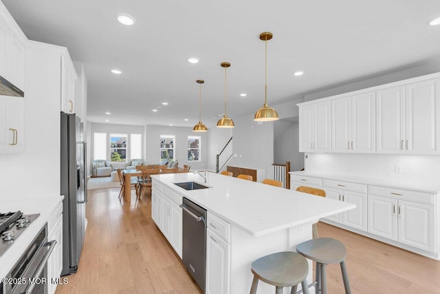 25 Signal Ave, Oceanport, NJ 07757 - kitchen featuring stainless steel appliances, a breakfast bar area, white cabinets, a kitchen island with sink, and light wood-style floors