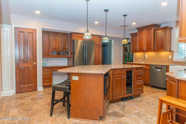 223 Kelly Lynn Ln, Brick, NJ 08724 - kitchen featuring appliances with stainless steel finishes, brown cabinetry, decorative backsplash, wine cooler, and a kitchen island