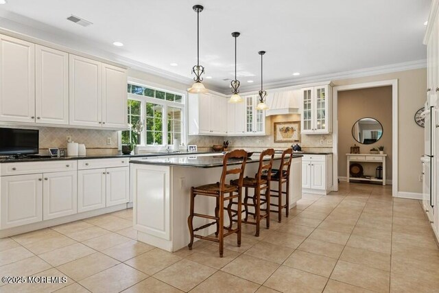 9 Wide Horizons Dr, Colts Neck, NJ 07722 - kitchen featuring decorative backsplash, light tile patterned floors, crown molding, a breakfast bar area, and dark countertops