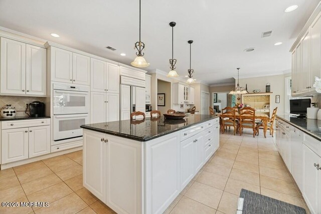 9 Wide Horizons Dr, Colts Neck, NJ 07722 - kitchen featuring paneled built in refrigerator, white double oven, light tile patterned floors, a kitchen island, and ornamental molding