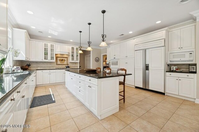 9 Wide Horizons Dr, Colts Neck, NJ 07722 - kitchen featuring built in appliances, light tile patterned floors, a kitchen island, glass insert cabinets, and a breakfast bar area