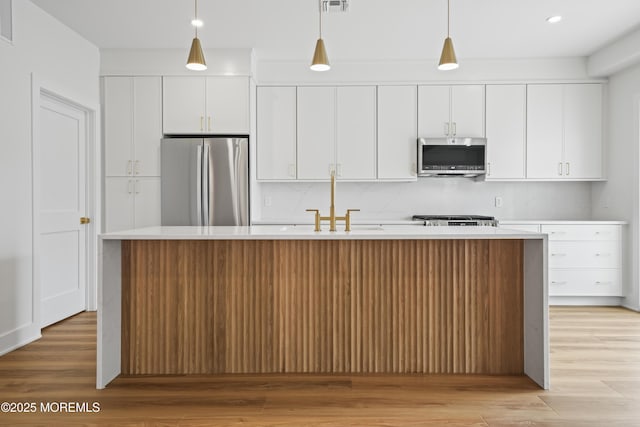 33 Hamilton Ave Unit 7, Seaside Heights, NJ 08751 - kitchen with stainless steel appliances, a center island with sink, white cabinetry, light countertops, and light wood-style floors