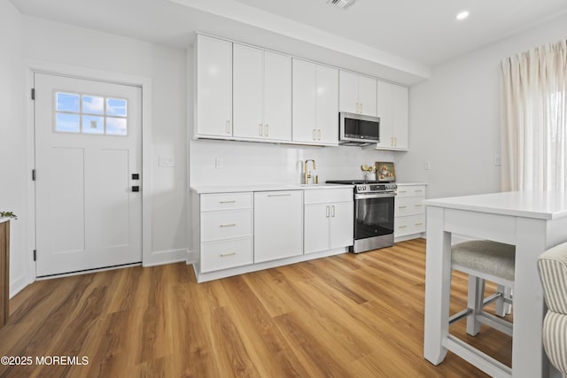 33 Hamilton Ave Unit 7, Seaside Heights, NJ 08751 - kitchen with stainless steel appliances, light countertops, light wood-style floors, recessed lighting, and white cabinetry