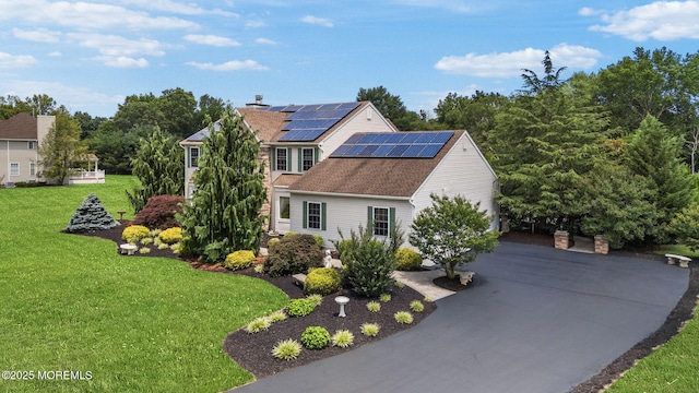 32 Langeveld Dr, Freehold, NJ 07728 - view of front of home featuring roof mounted solar panels, a front yard, driveway, and a shingled roof