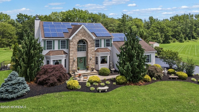 32 Langeveld Dr, Freehold, NJ 07728 - traditional-style house featuring a front yard, a chimney, roof mounted solar panels, and stone siding