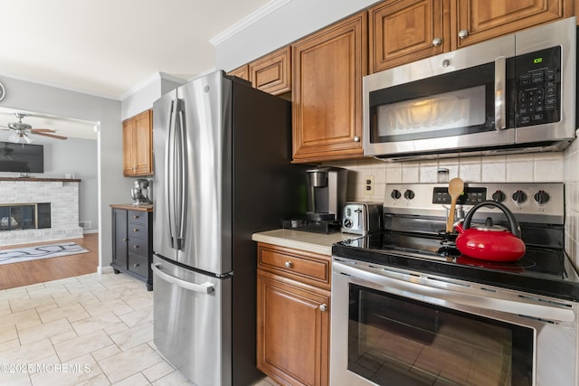 3 Thompson Ln, Manalapan, NJ 07726 - kitchen with appliances with stainless steel finishes, ceiling fan, brown cabinetry, crown molding, and tasteful backsplash