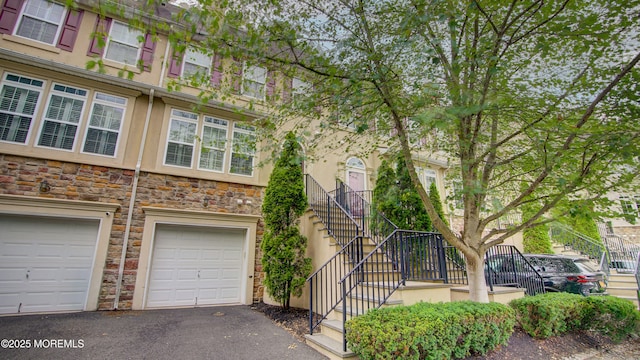 56 W Aspen Way, Aberdeen, NJ 07747 - townhome / multi-family property with stone siding, stairs, driveway, and an attached garage