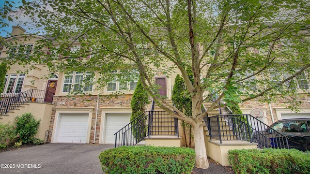 56 W Aspen Way, Aberdeen, NJ 07747 - townhome / multi-family property featuring stairs, stone siding, driveway, and a garage