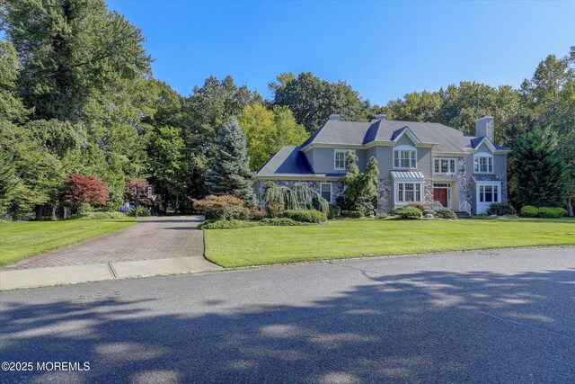26 Bruns Rd, Allenhurst, NJ 07711 - view of front facade featuring a front lawn, driveway, stone siding, and a chimney