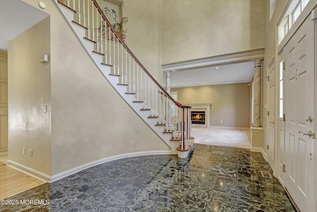 26 Bruns Rd, Allenhurst, NJ 07711 - foyer entrance featuring marble tiled flooring, stairs, a warm lit fireplace, a high ceiling, and crown molding